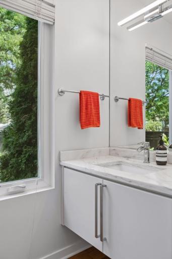Main floor powder room, with white marble counter and frosted pocket door.