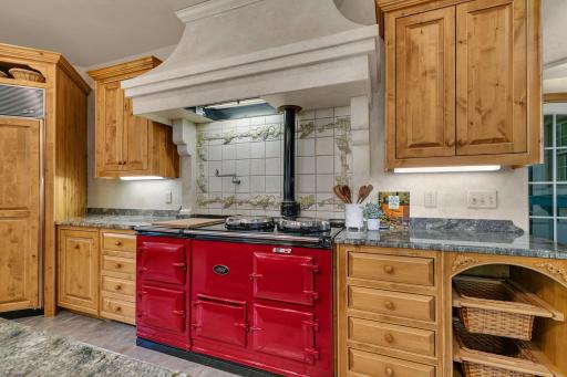 The heart of the kitchen is the iconic AGA range, a timeless centerpiece that blends classic British craftsmanship with everyday functionality. Renowned for its cast-iron construction and radiant heat cooking.
