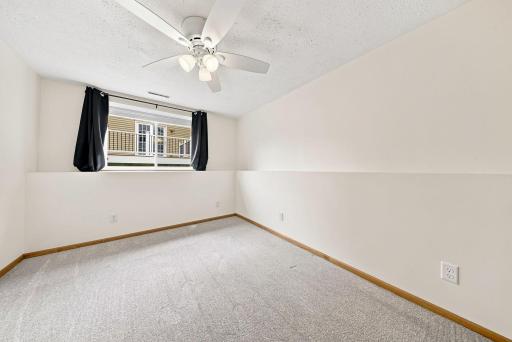 Spacious lower-level bedroom with large daylight window and fresh finishes makes an ideal guest room, office, or hobby space.
