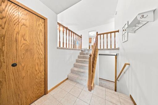 Bright, welcoming foyer with tile flooring, coat closet, and split-entry design.