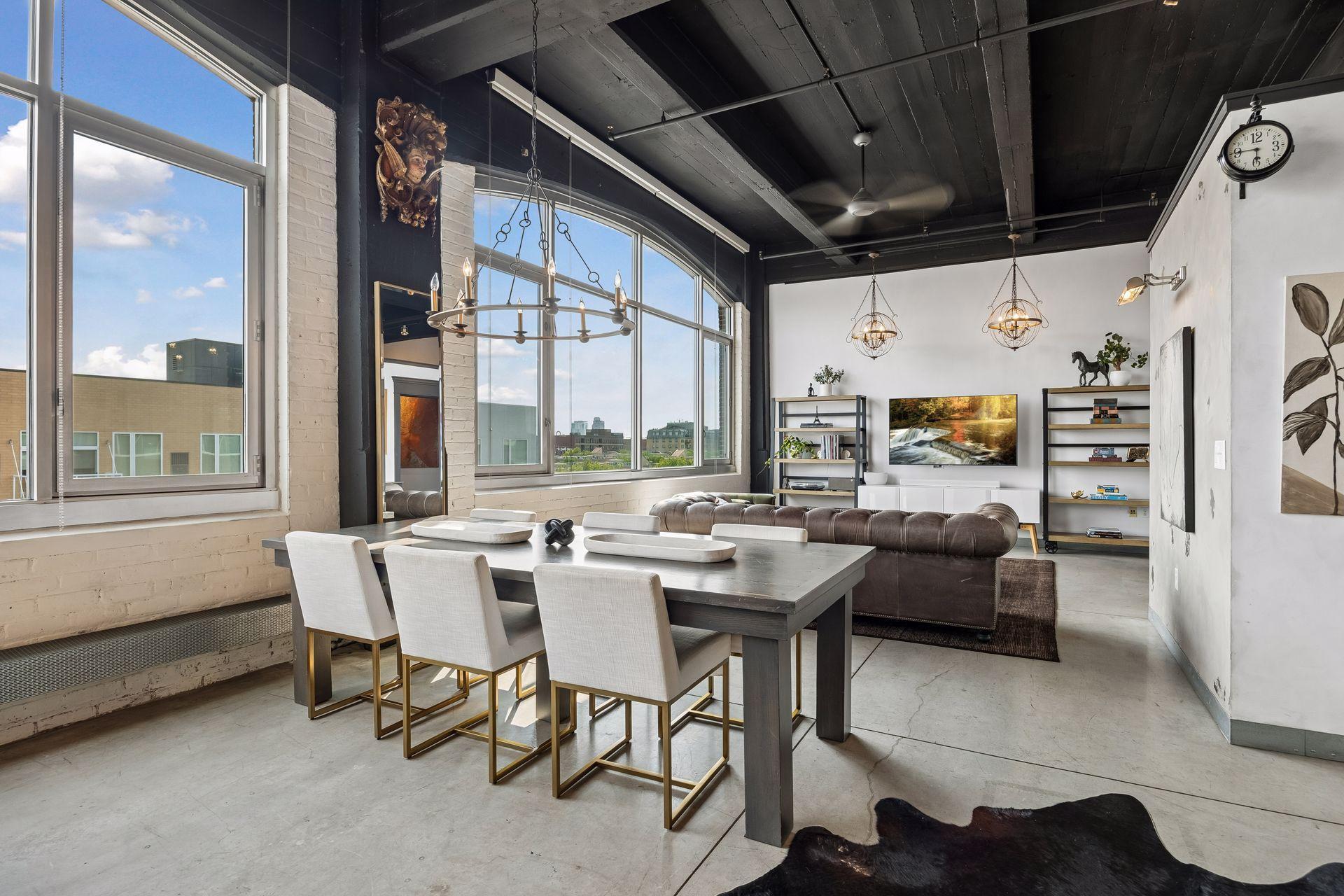 From the kitchen, the living and dining areas unfold toward a striking media wall, with a dramatic expanse of arched windows drawing in natural light from the left.