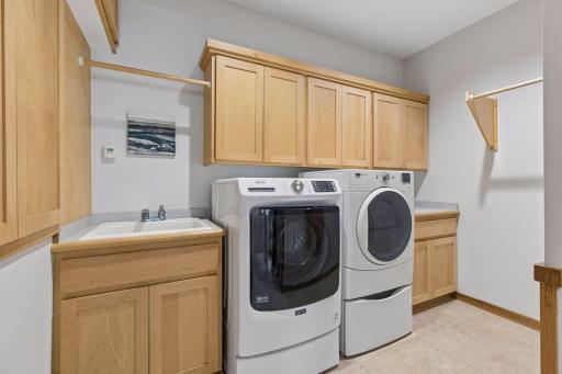 Laundry room with maple cabinetry and sink with tiled floor just off the mudroom