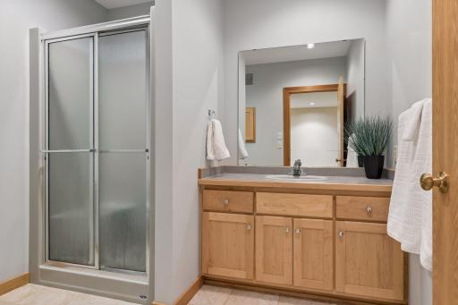 The main 3/4 bathroom on the lower level with tiled flooring and maple cabinetry