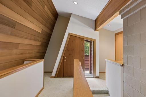 Architecturally angled redwood wall with creatively designed and angled heavy wood cut doors leading to a 2nd-level deck for a bird's-eye view of the property