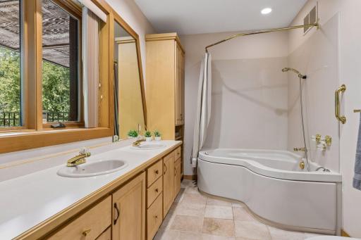 Primary bathroom with an abundant wall of windows and a double sink. Tiled flooring