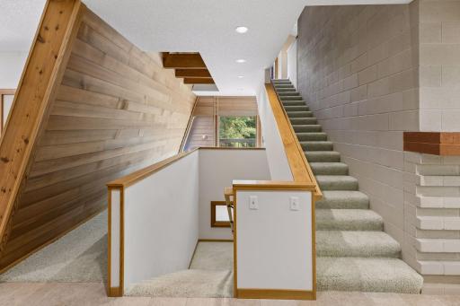 Architecturally angled redwood wall with open ceilings soaring 18 feet high, leading to the upper level