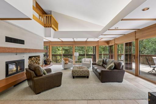 Living room with an 18-foot open ceiling, wood fireplace, and glass walls all around, making this room a large sunroom
