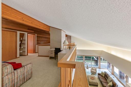 Mezzanine loft area with a view of the living room and kitchen below. Massive micro-beam support along the ceiling