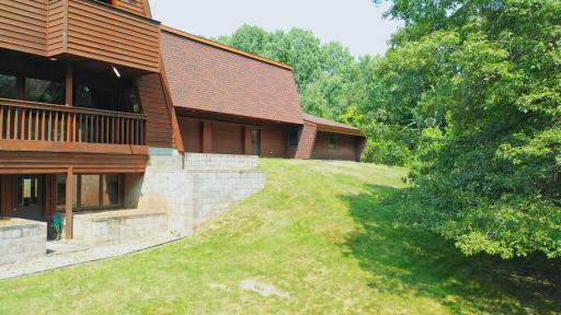 The backside of the home shows the walk-out lower-level door, the two overhead garage doors, and two exterior doors leading to the backyard, patio, and deck.