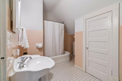 Classic bathroom with a tub/shower combination, traditional fixtures, and tiled flooring.