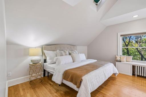 Serene bedroom with vaulted ceilings, hardwood floors, and soft natural light.