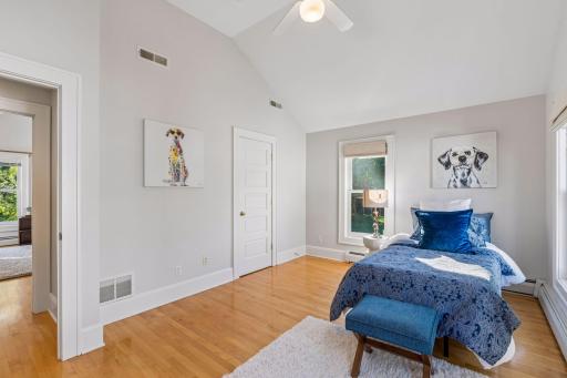 Bright bedroom with blue accents, framed artwork, and ample natural light.