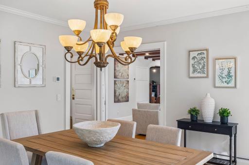 Close-up view of the dining area highlighting the chandelier, artwork, and tailored finishes.