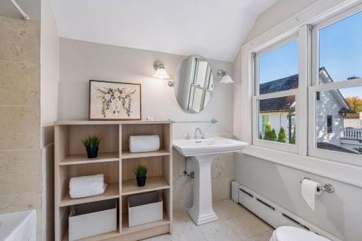 Charming bathroom with a pedestal sink, built-in shelving, and abundant natural light.