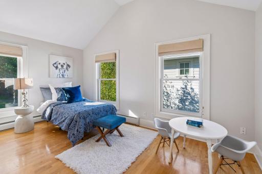 A bedroom featuring rich blue accent palettes, hardwood floors, and a comfortable sitting area.