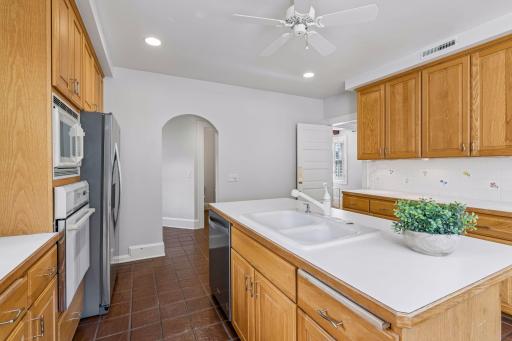 Bright kitchen workspace featuring ample counter space, tailored cabinetry, and a graceful arched doorway.