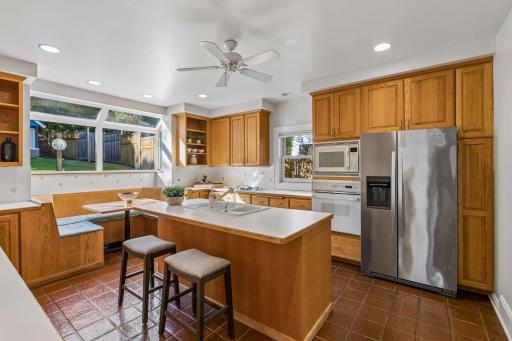 Spacious kitchen centered around a large island with seating, abundant cabinetry, and stainless-steel appliances.
