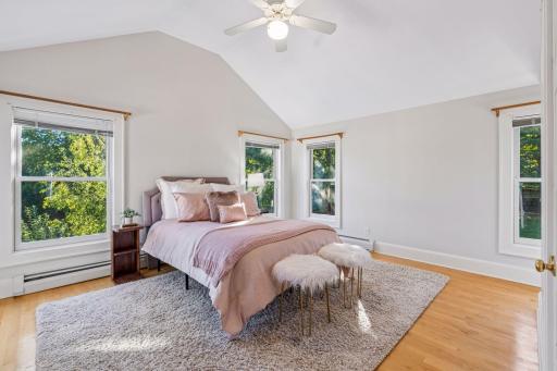 Softly appointed bedroom with warm blush tones, hardwood floors, and generous windows.