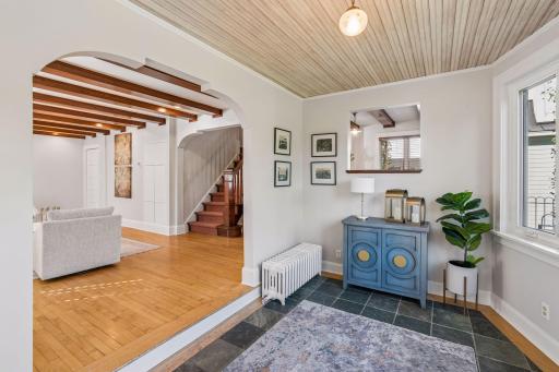 Welcoming interior entry with a painted cabinet, hardwood floors, and views toward the staircase.