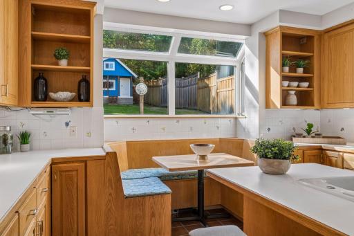 Bright kitchen breakfast nook with built-in cabinetry, a window seat, and leafy views.