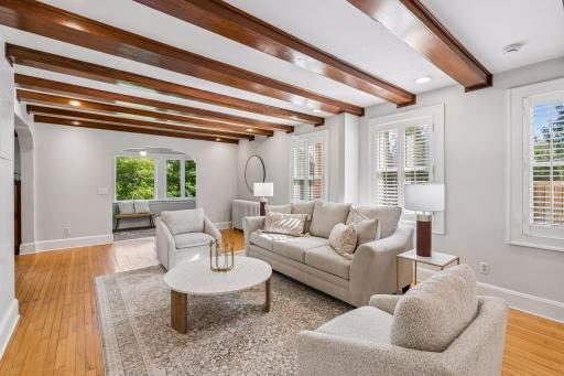Light-filled living room featuring exposed wood beams, hardwood floors, and generous seating.