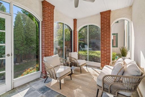 Bright enclosed porch surrounded by expansive windows and peaceful garden views.