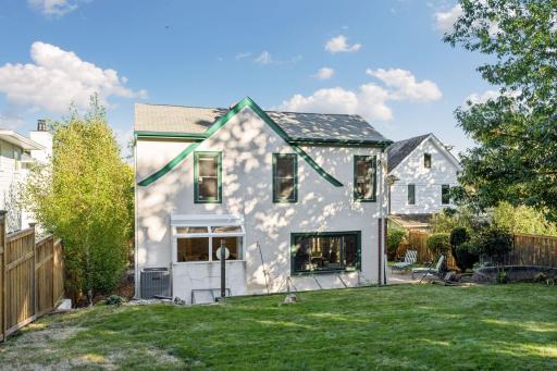 Rear elevation framed by mature trees and a spacious green lawn.