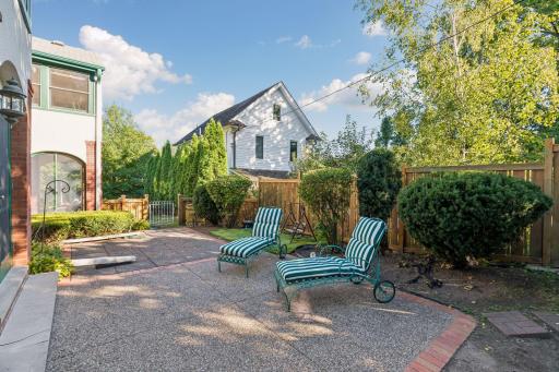 Expansive backyard terrace with Adirondack-style seating and mature greenery.