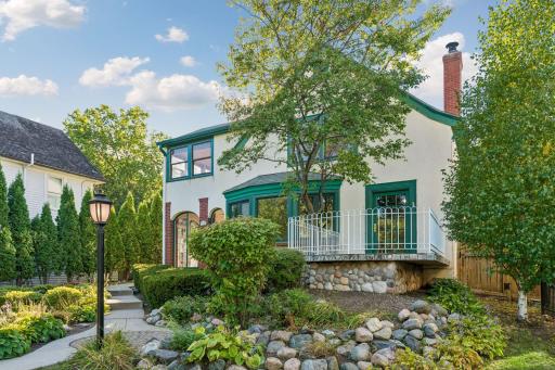 Charming side elevation with landscaped gardens, stonework, and an elevated terrace.