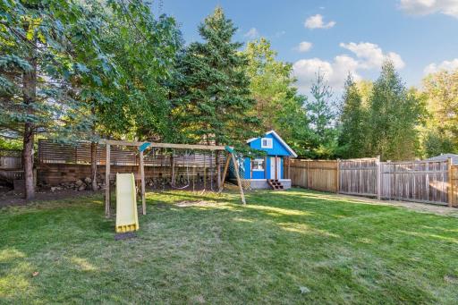 Lush backyard with a play area, lawn space, and a charming garden setting.
