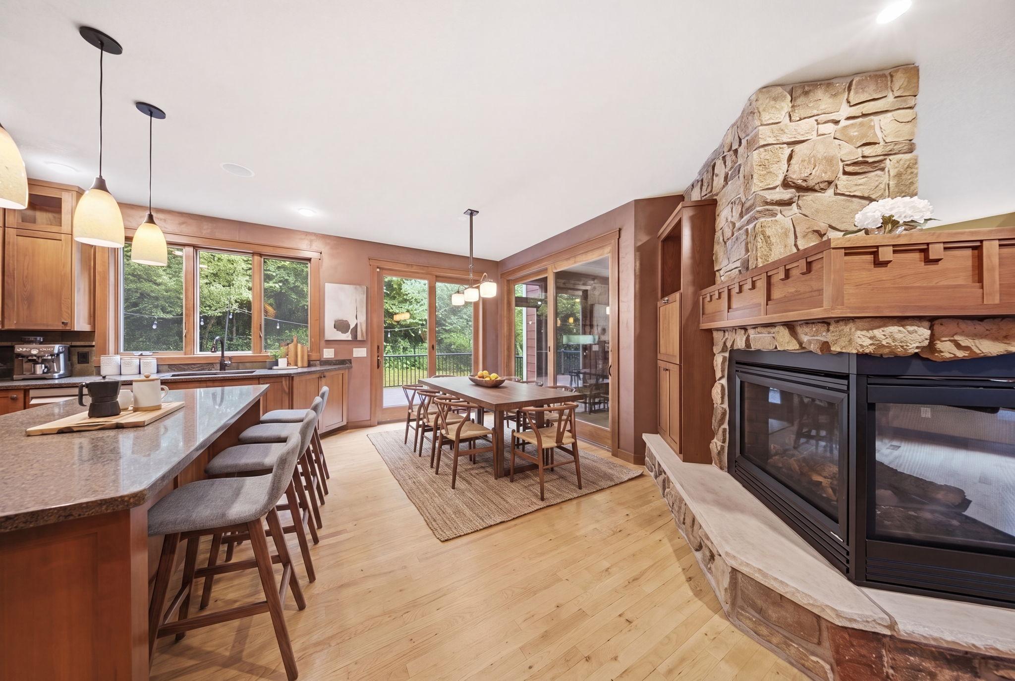 The dining area and living room share a cozy double-sided fireplace and access to the maintenance-free deck . (virtually staged)