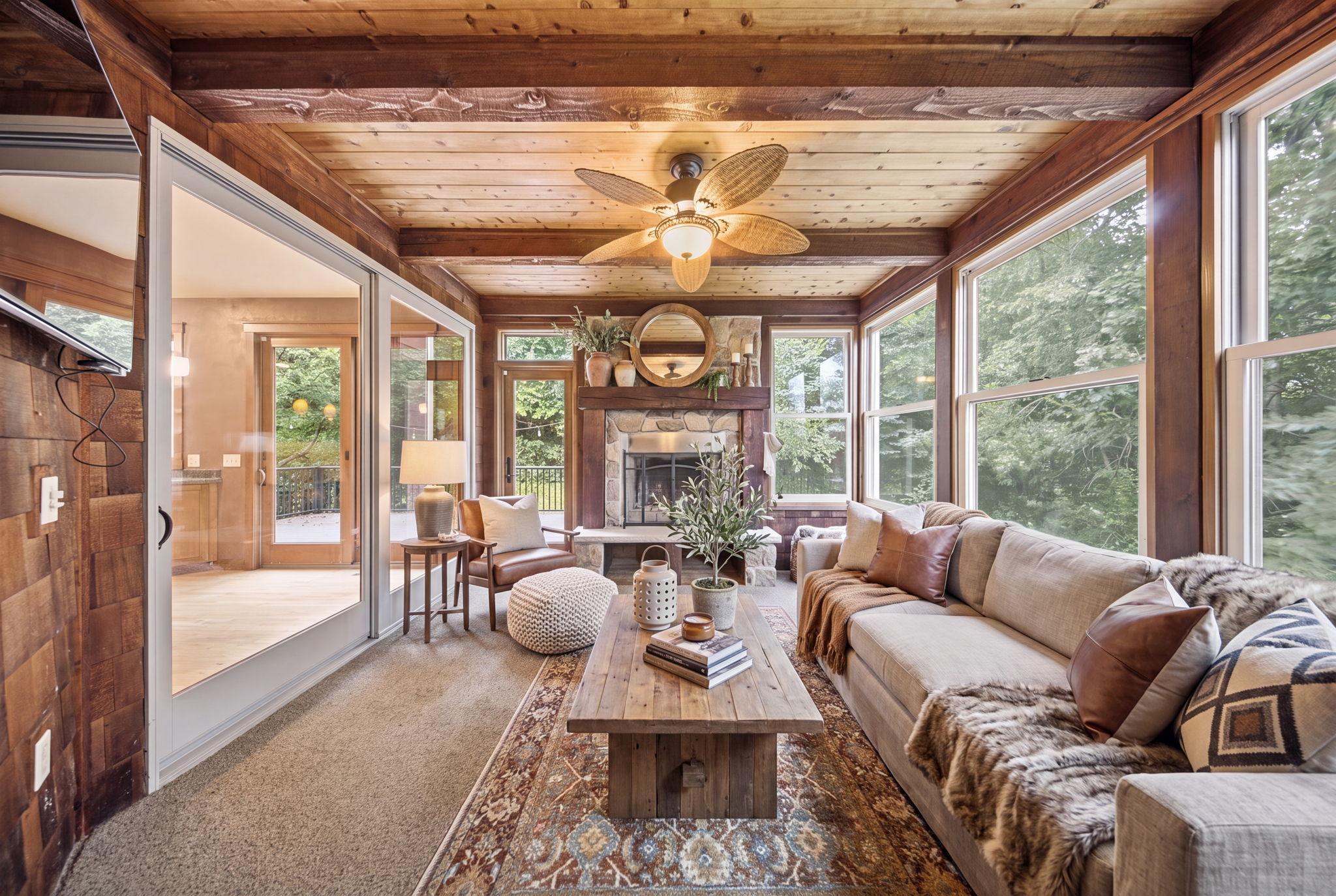 Rustic four-season room offering the ideal spot to unwind year round with a wood-burning fireplace and peaceful wooded views. (virtually staged)