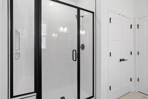 A glass-enclosed shower offers a spa-like experience in the en-suite bathroom
