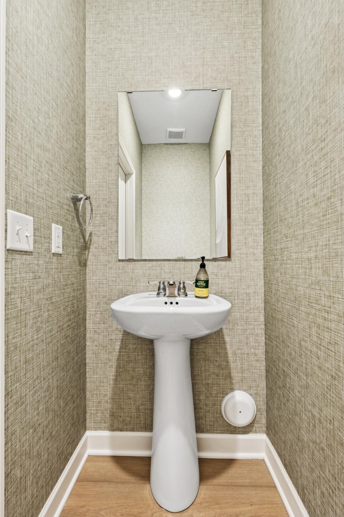 (Photo of model home, features will vary). Situated directly off the kitchen, this powder room optimizes the first-floor main living area for residents and guests alike.