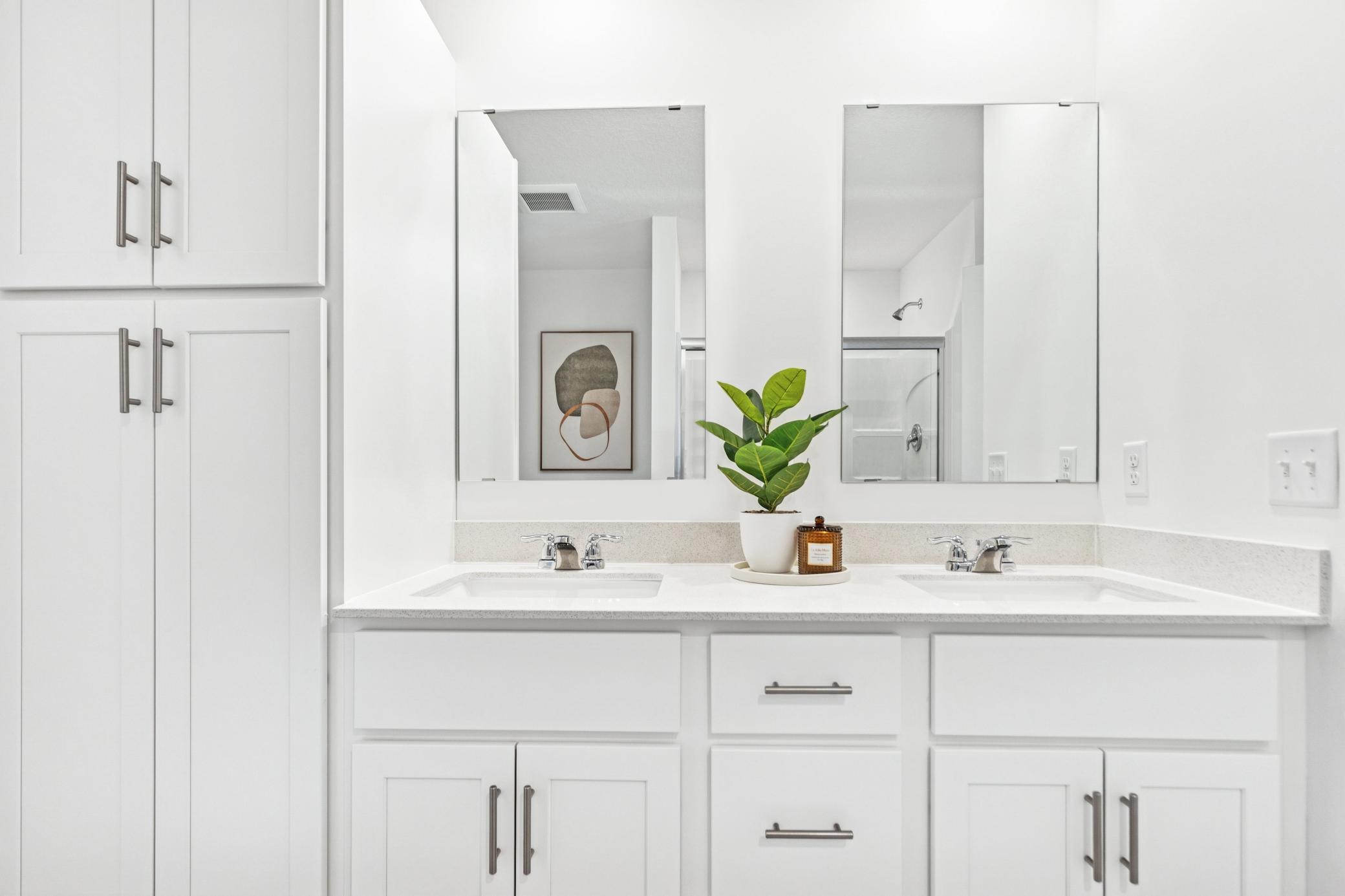 (Photo of model home, features will vary) Featuring a glass-enclosed shower with built-in shelving and glass mirrors set atop dual quartz sinks and vanity-cabinetry, the en-suite bathroom helps streamline morning routines