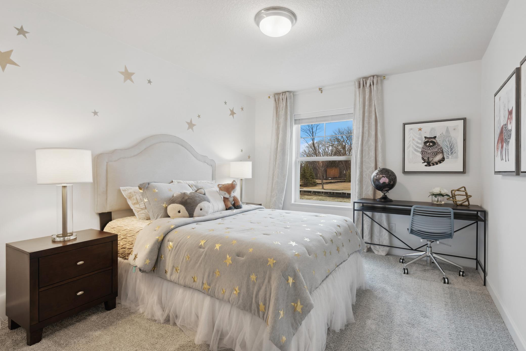 (Photo of decorated model, actual home's finishes vary) One of two generously sized upper level secondary bedrooms with spacious closets.