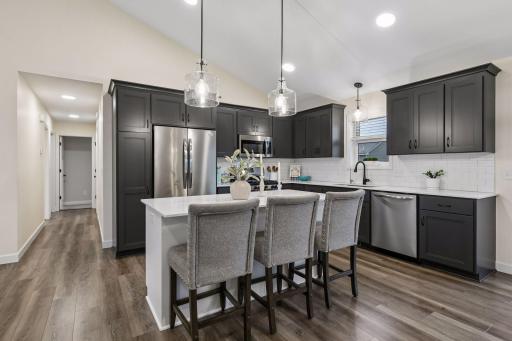 Designed to impress and built for everyday living, this beautiful kitchen features upgraded cabinetry, quartz countertops, a timeless tile backsplash, a gas range, and a spacious island perfect for gathering.