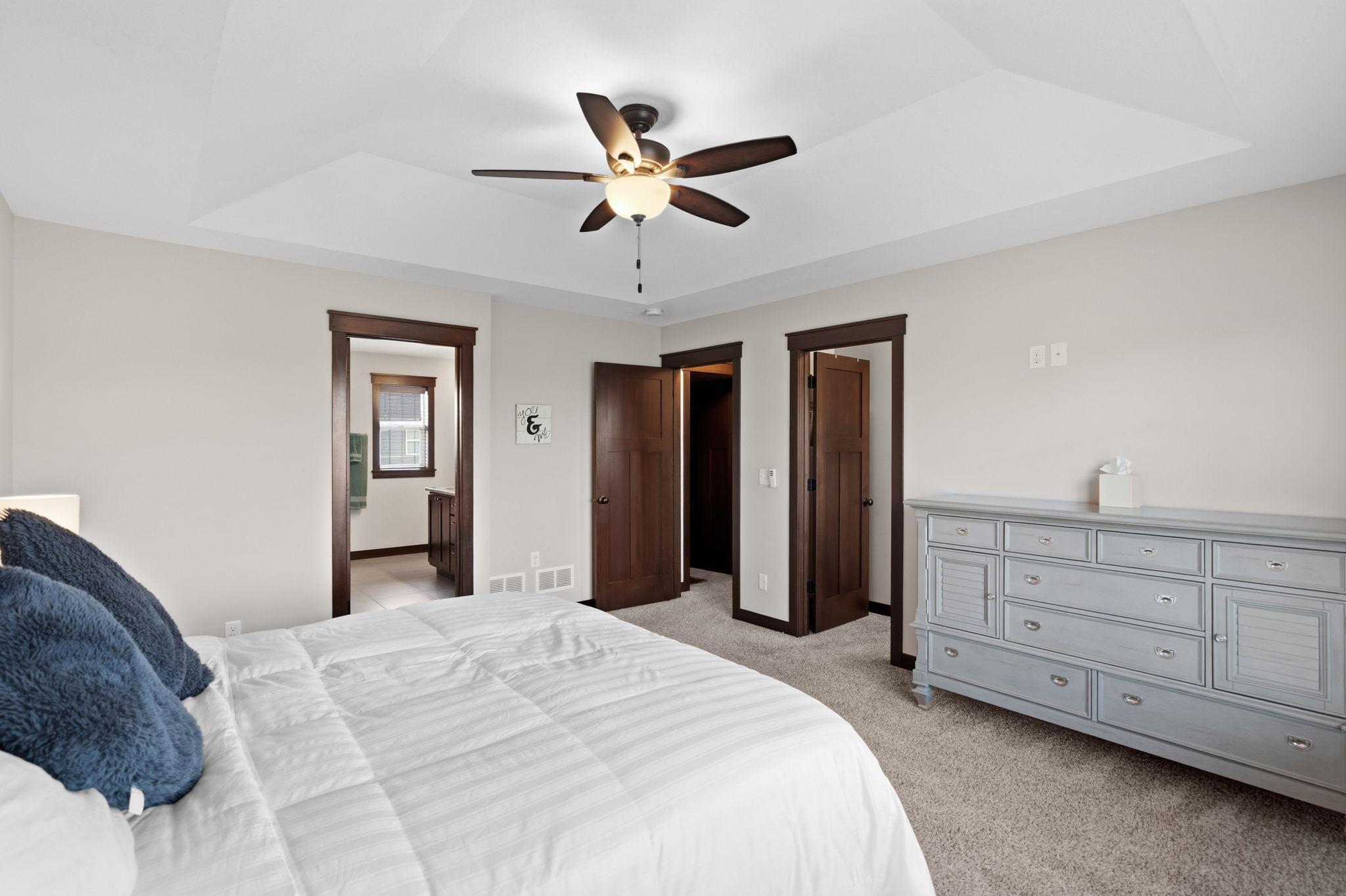 Primary suite featuring tray ceiling, neutral décor, and ample room for furnishings.