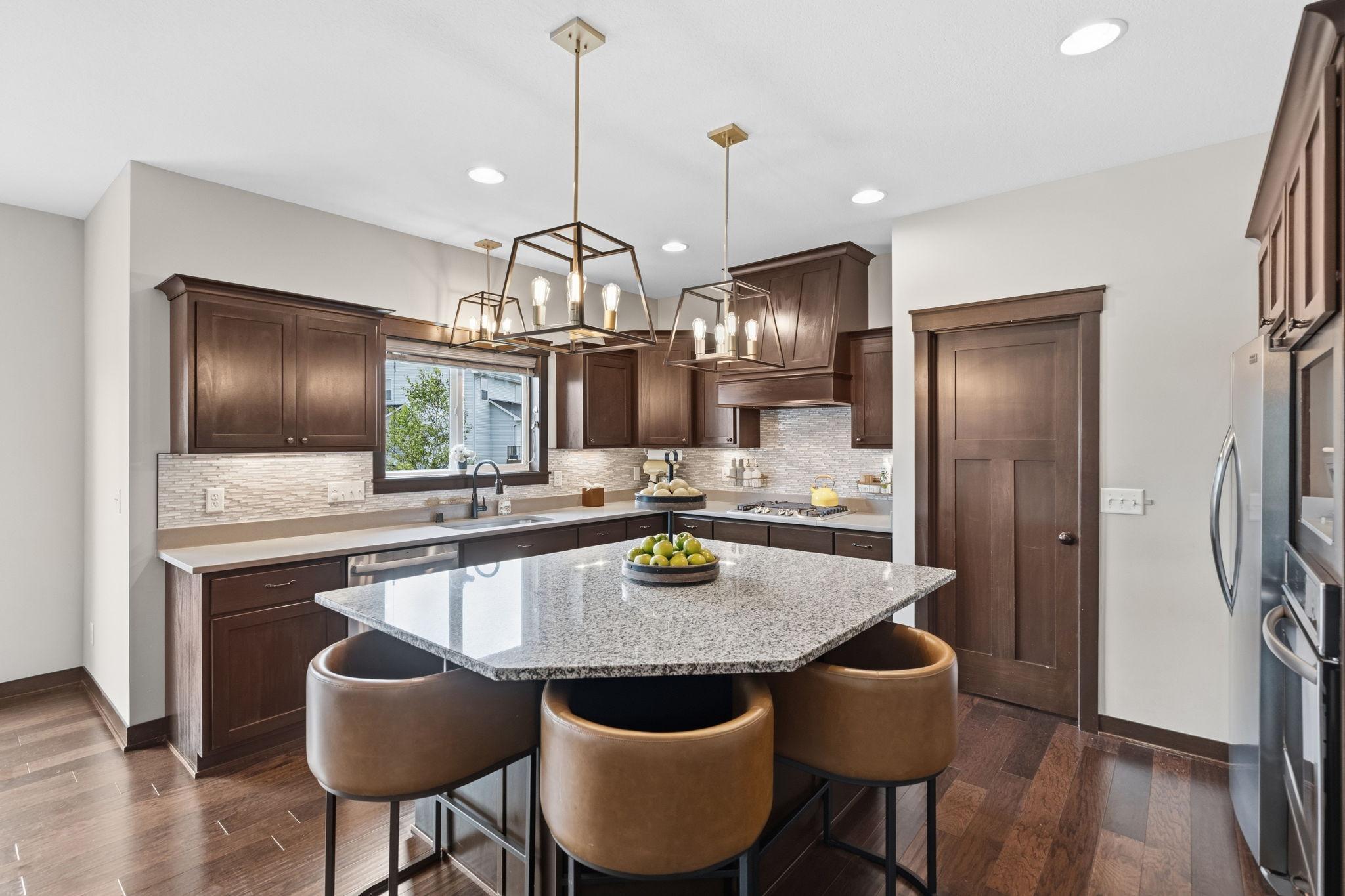 Gourmet kitchen featuring granite countertops, oversized center island, stainless steel appliances, and abundant cabinetry.