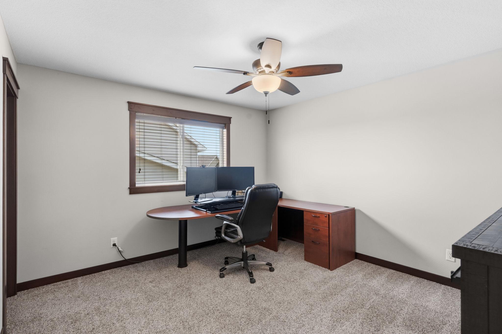 Spacious secondary bedroom with large window and ceiling fan.