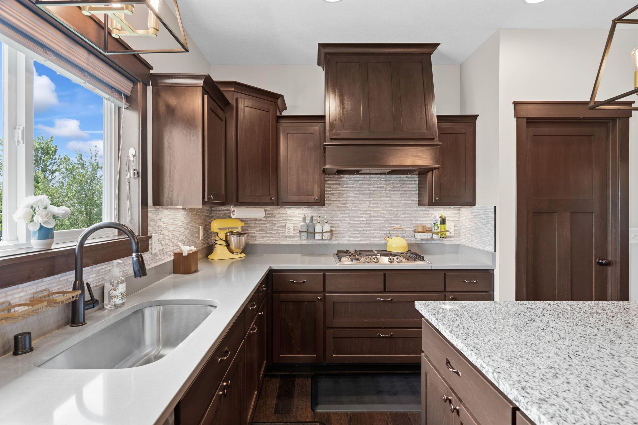 Functional kitchen featuring stainless steel appliances, tile backsplash, and ample prep space.
