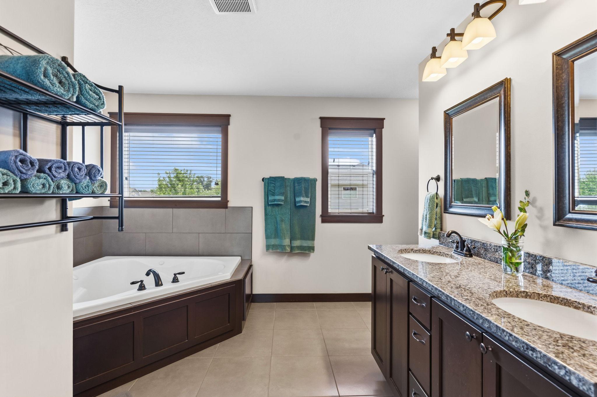Private owner's bath featuring dual vanities, large jetted tub, and abundant natural light.