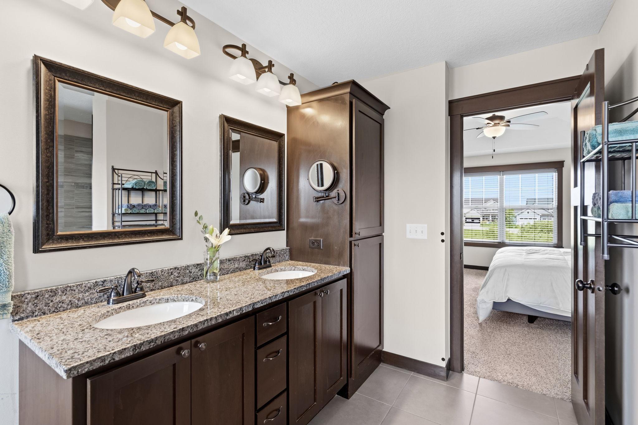 Dual-sink vanity with granite countertops and generous storage in the primary bath.