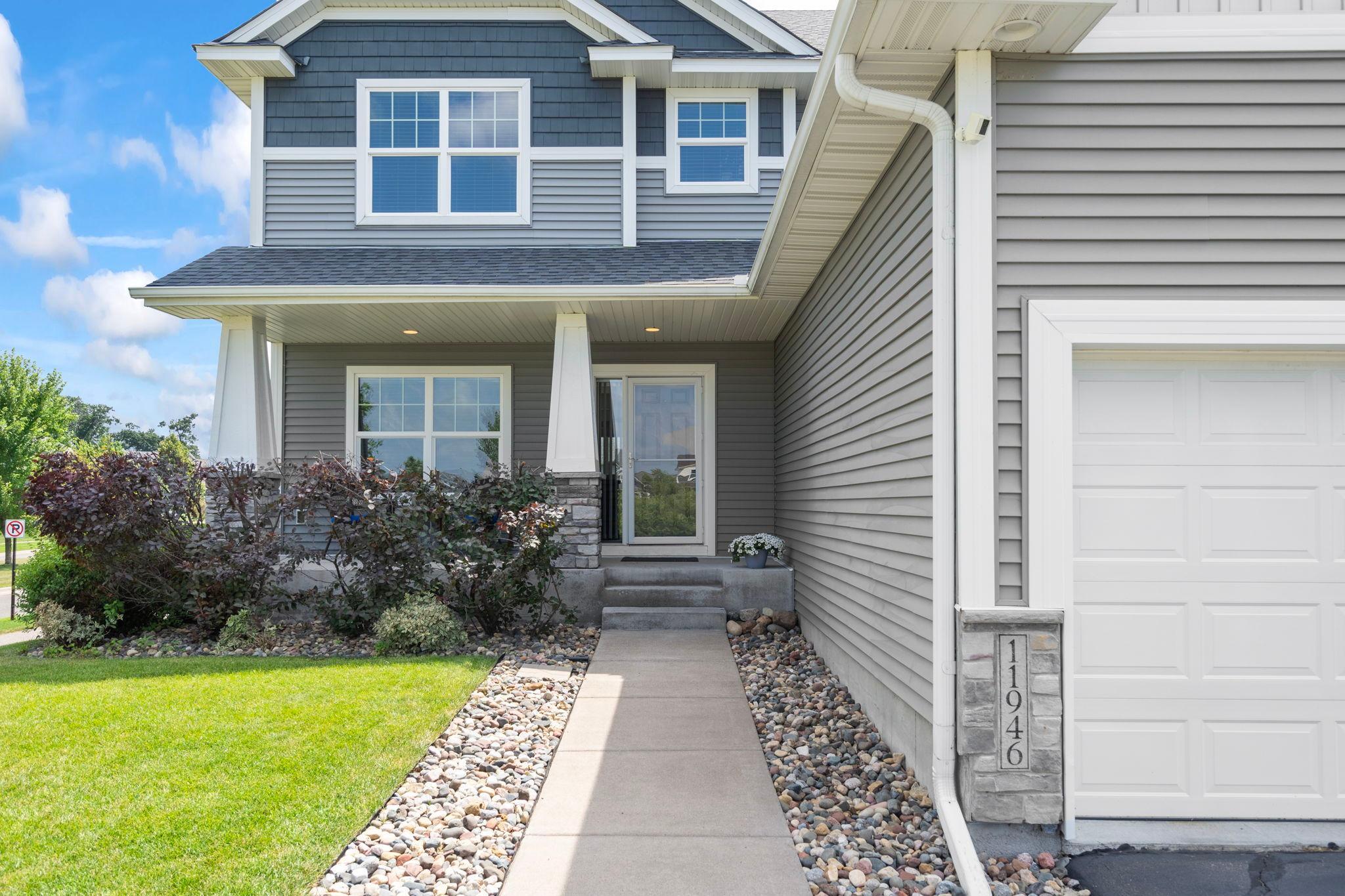 Inviting covered front entry with stone accents and landscaped walkway.
