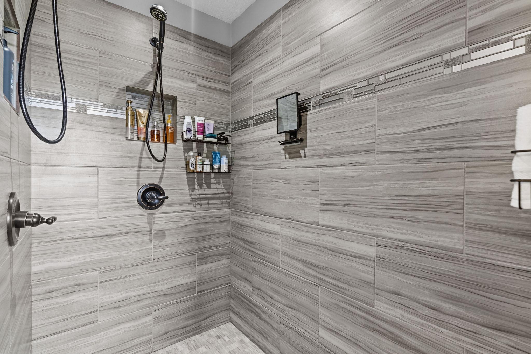 Oversized walk-in tiled shower with two shower heads and beautiful neutral finishes.
