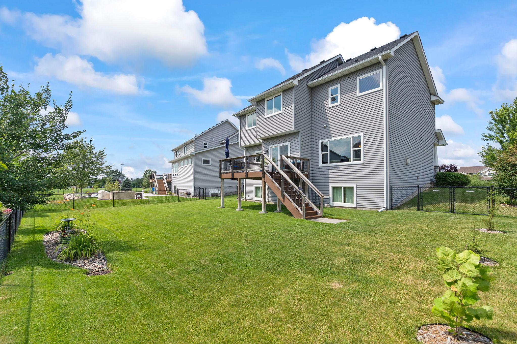 Expansive, flat backyard with deck stairs providing convenient access from the outdoor living space.