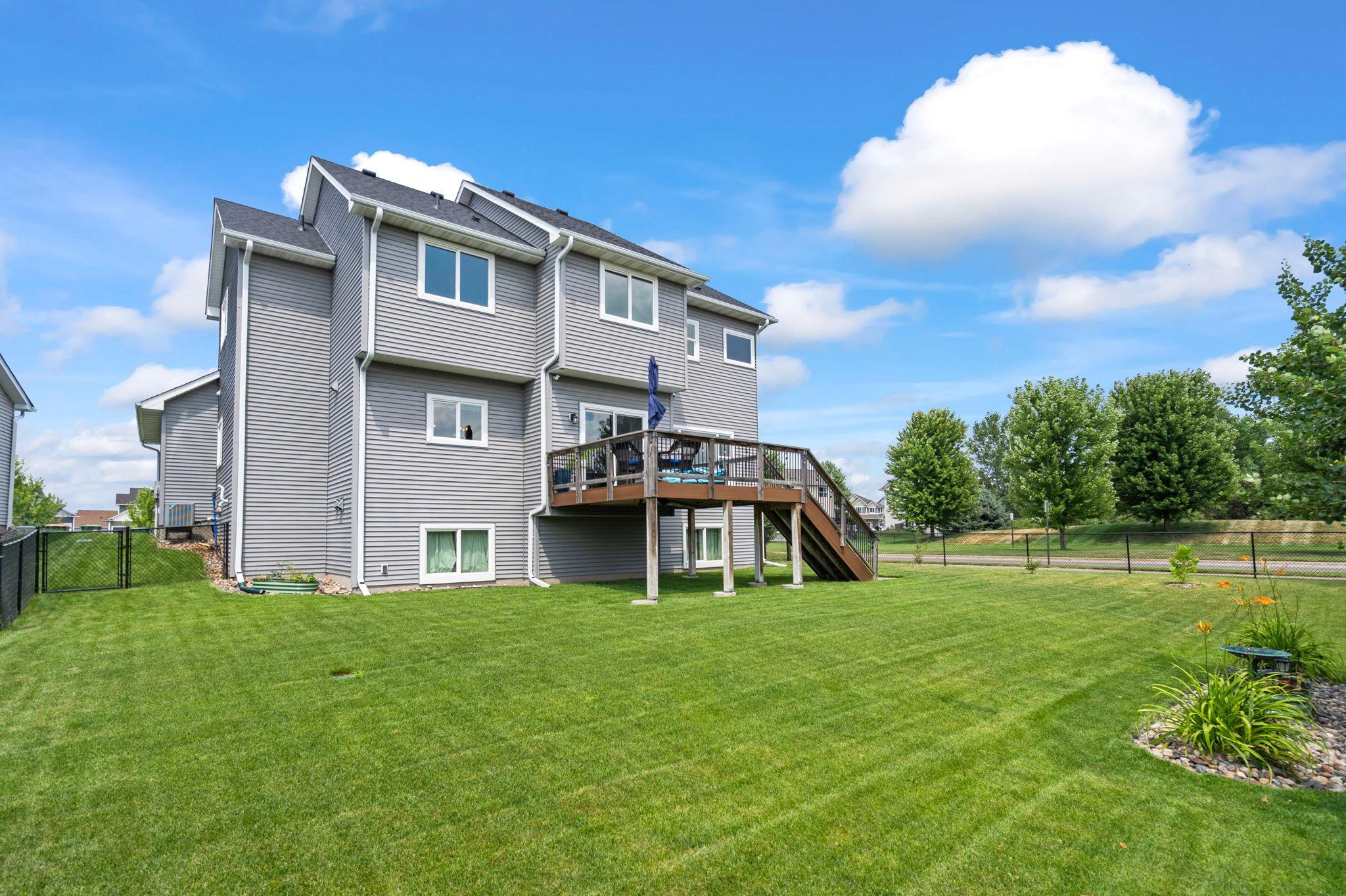Rear elevation showcasing the deck and beautifully maintained yard.