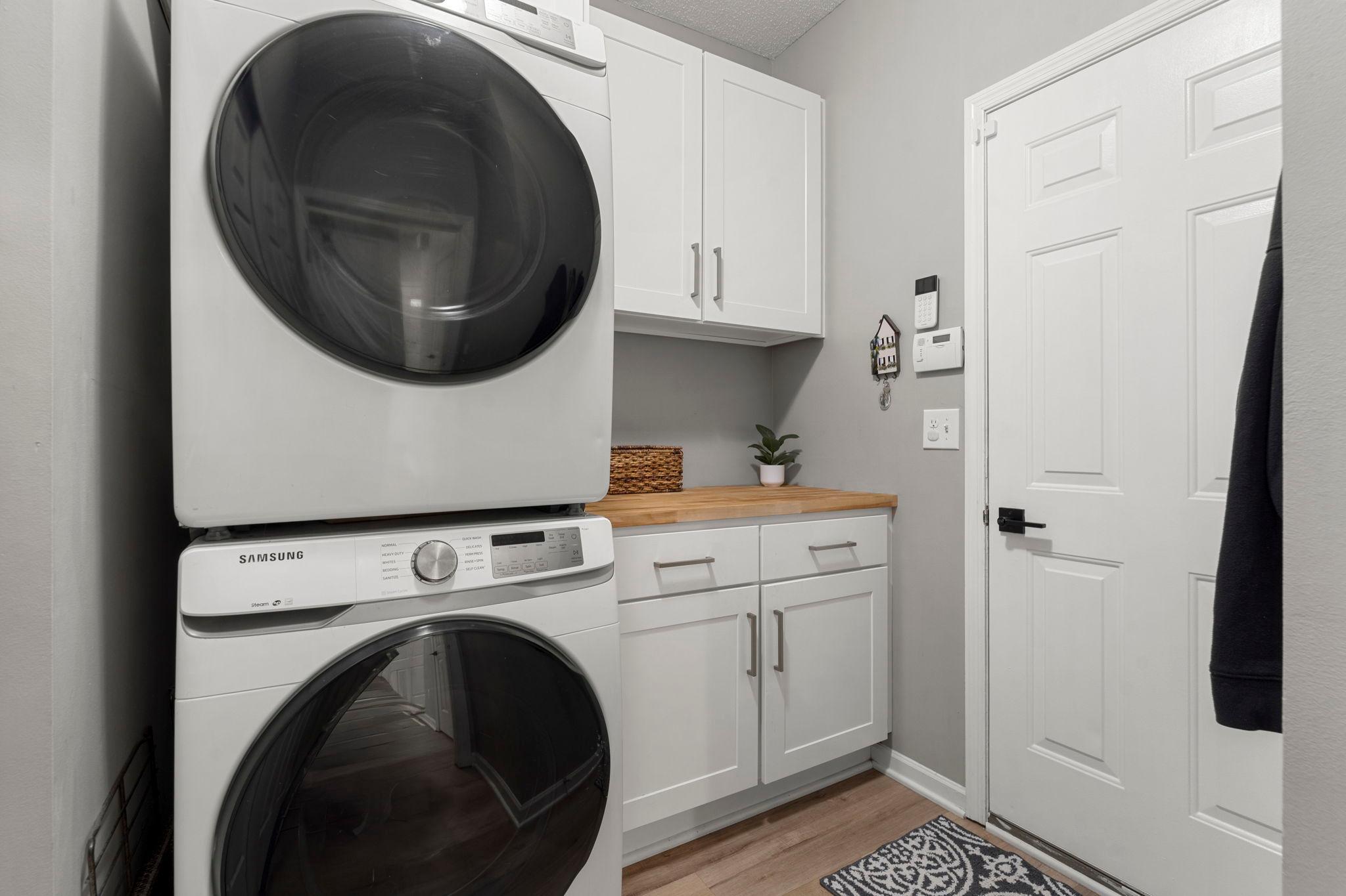 Completing the main level is a convenient laundry room and garage entry featuring a Samsung stackable washer and dryer, newly installed cabinetry, and countertop.