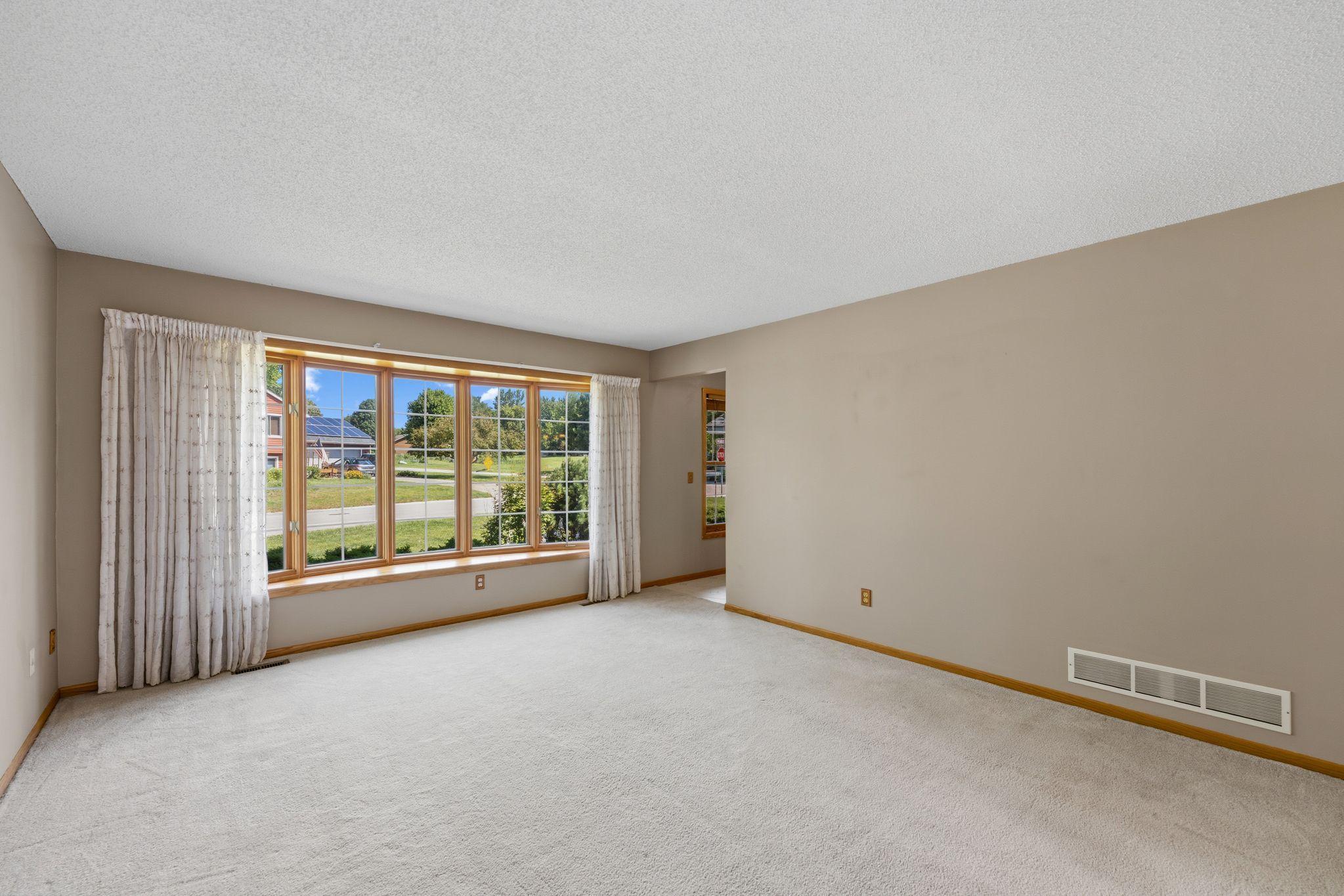Sunlight pours through the bow window, creating a bright and inviting first impression.