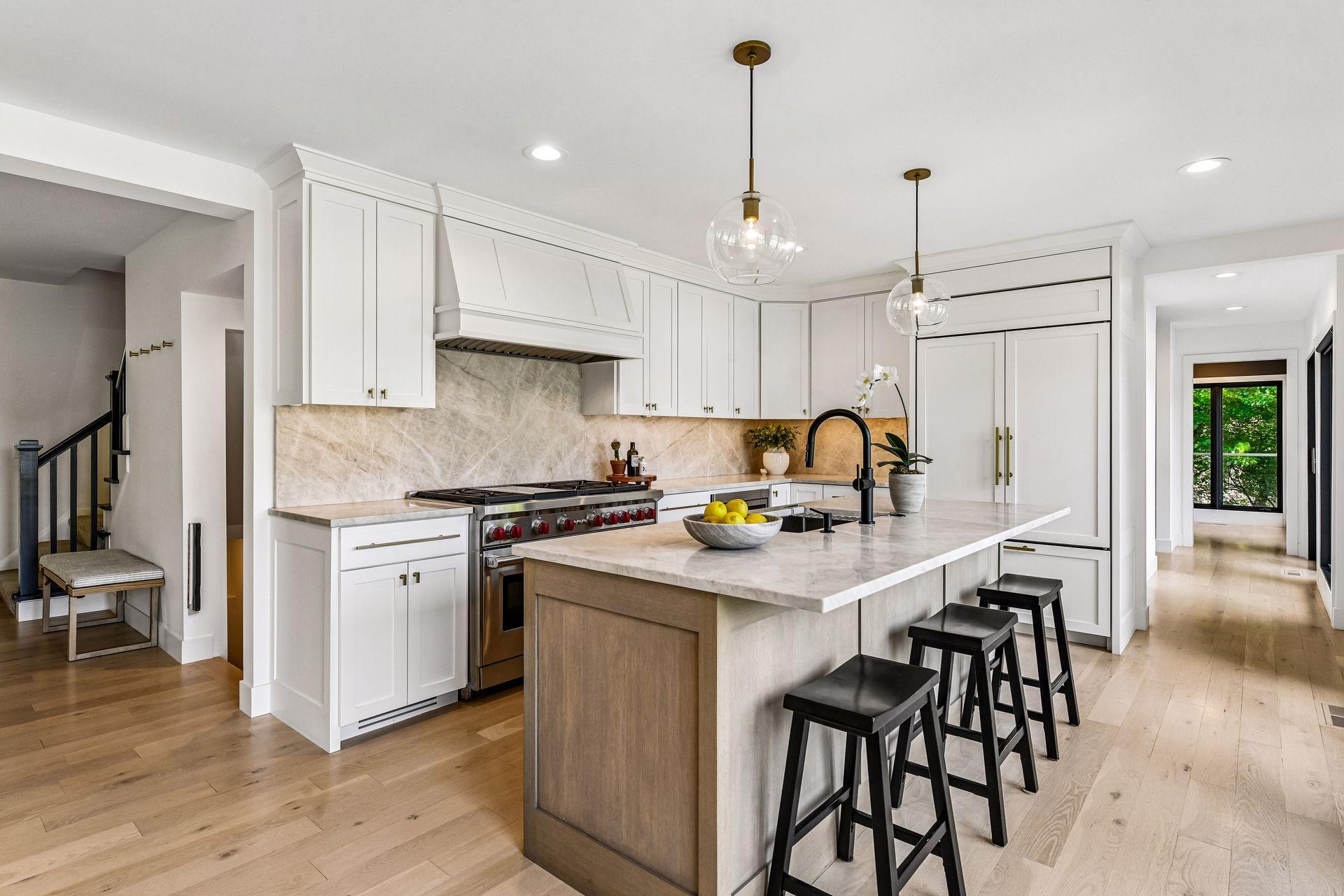 The gourmet eat-in kitchen is beautifully appointed with a center island, quartz countertops, custom enameled and stained cabinetry, and a Wolf gas range.